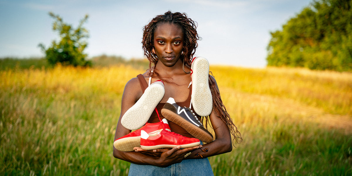 Model holding several colourways of the Manon barefoot trainer